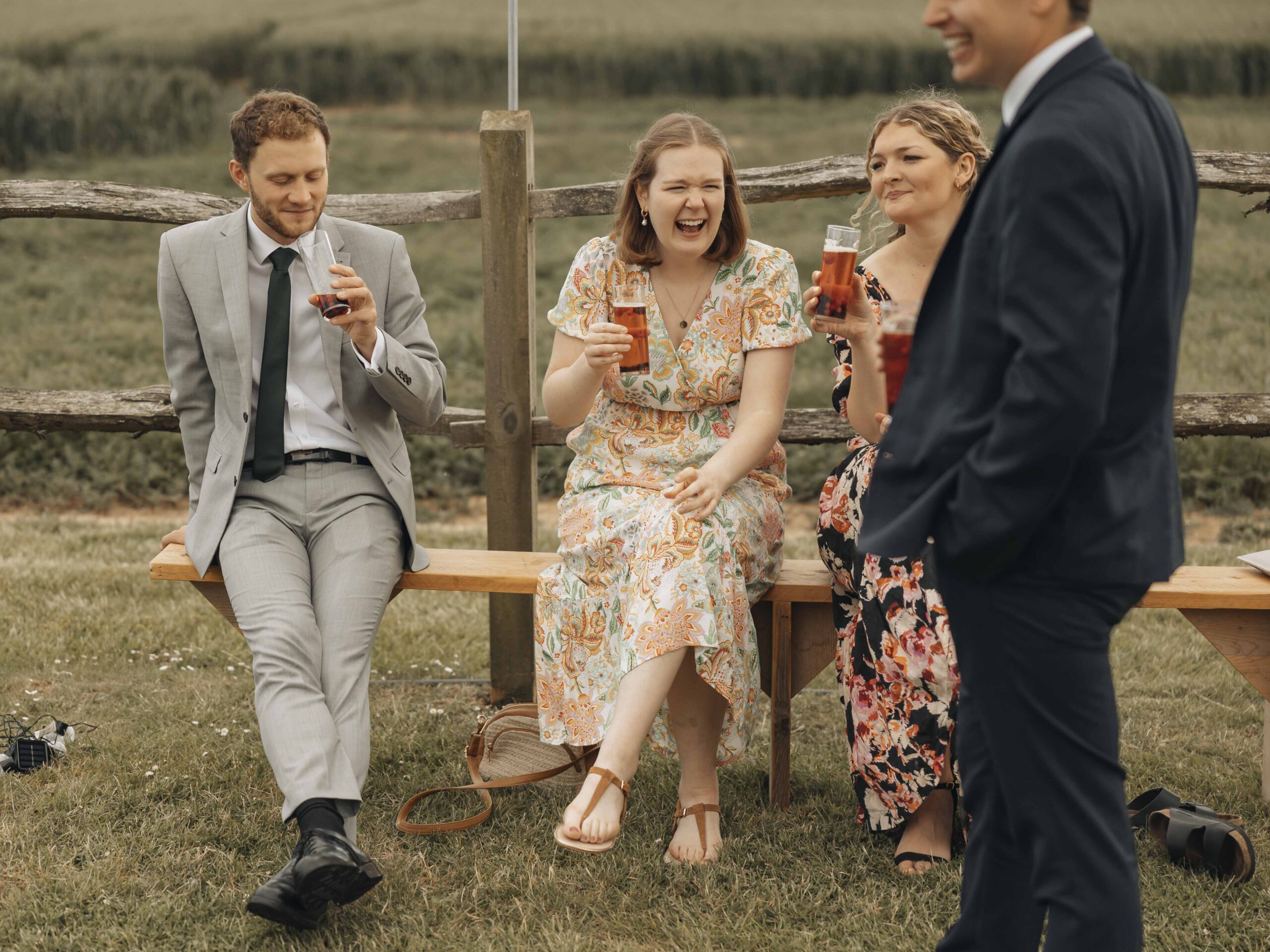 wedding guests laughing on a bench