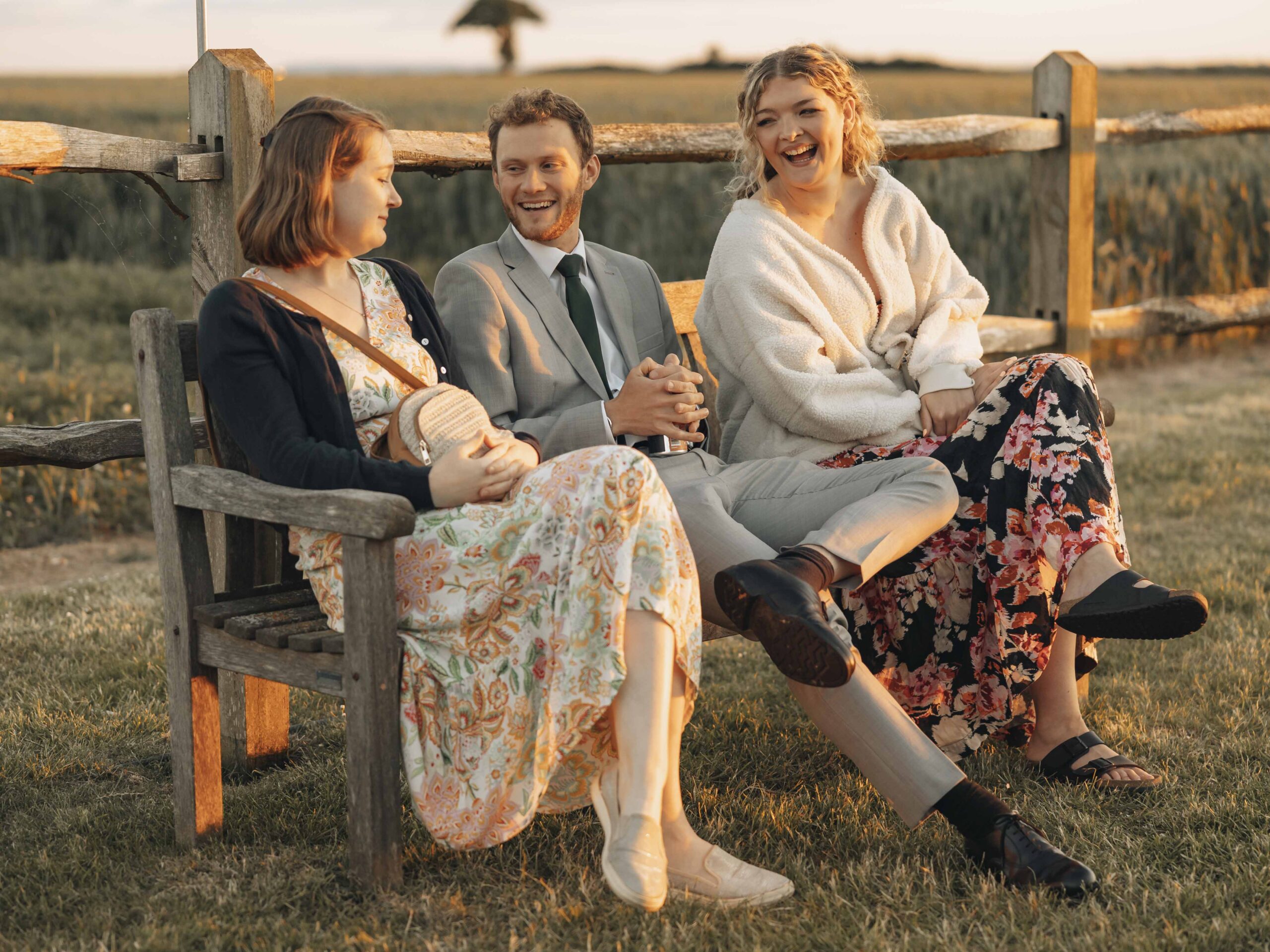 wedding guests laughing on a bench