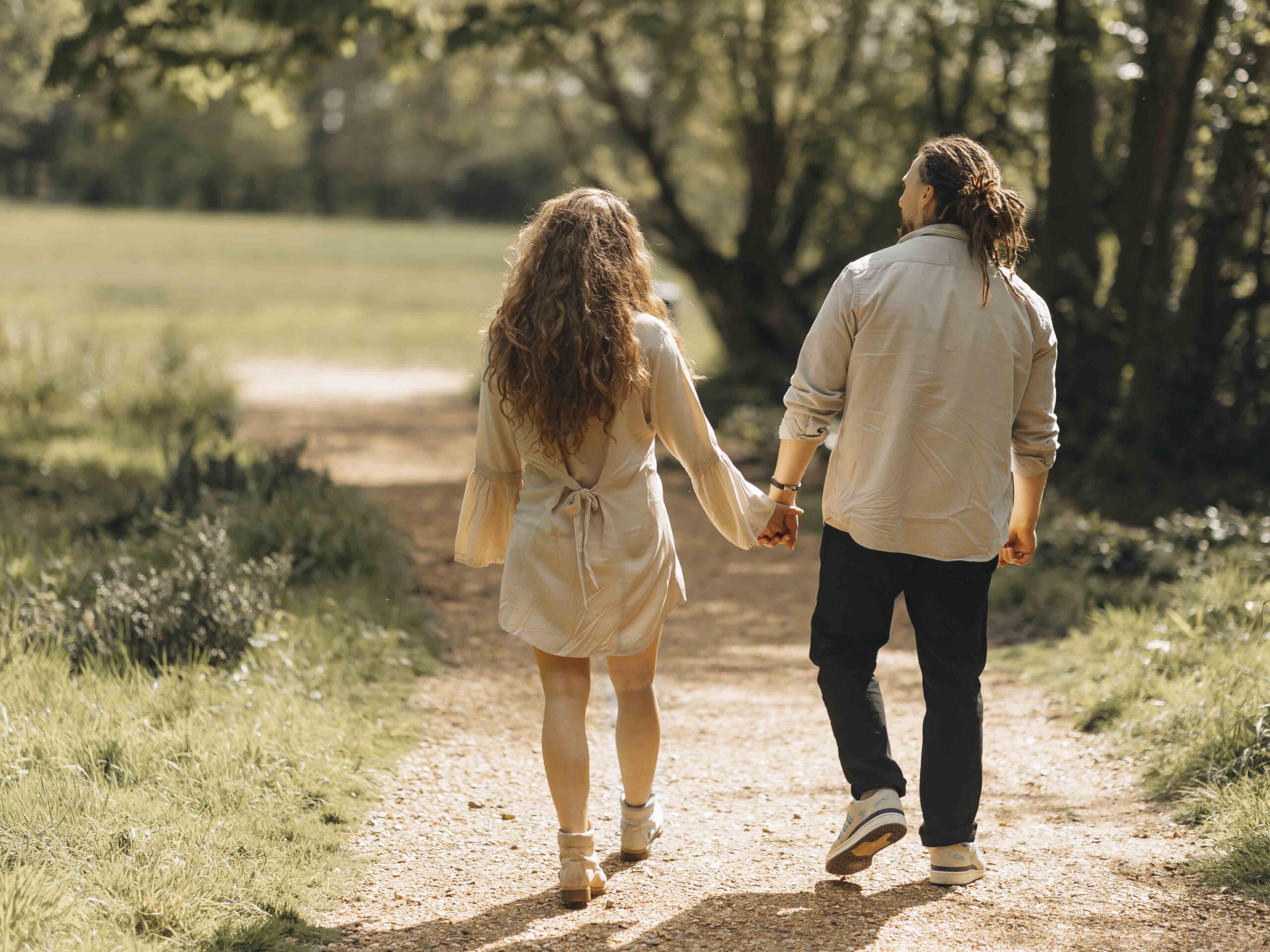 Couple holding hands walking through woods