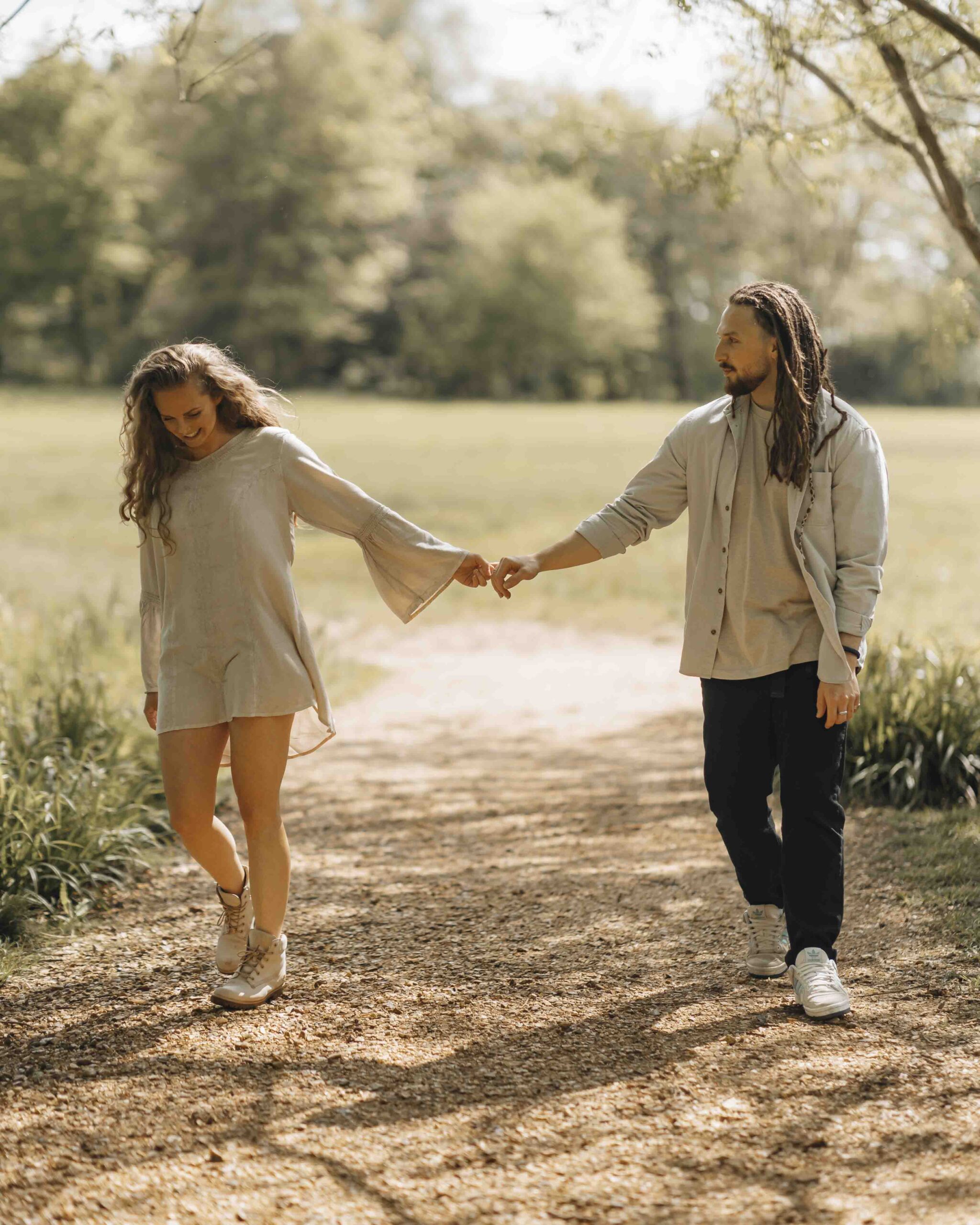 couple walking at arms length and smiling in woods