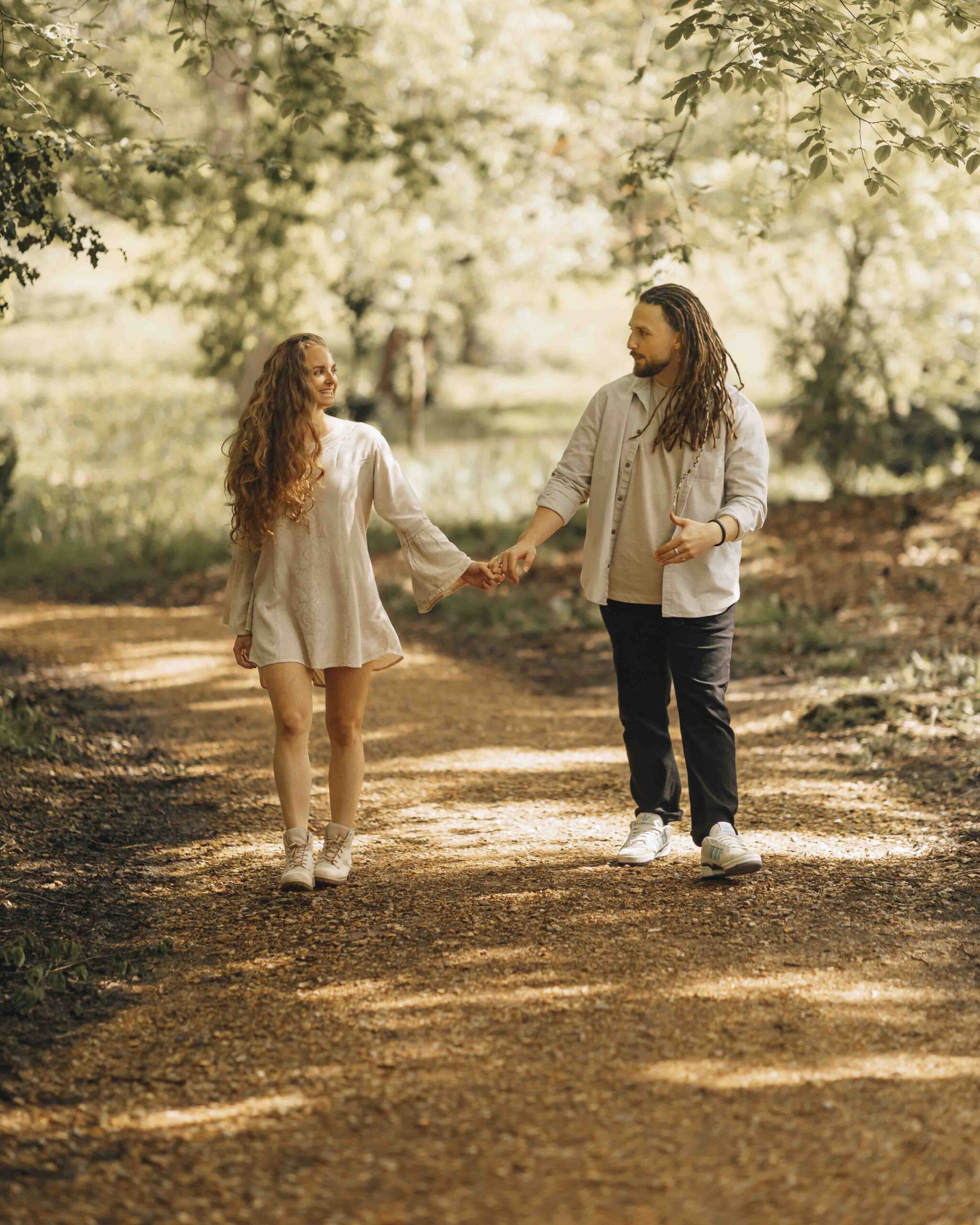 couple holding hands and walking on a woodland path