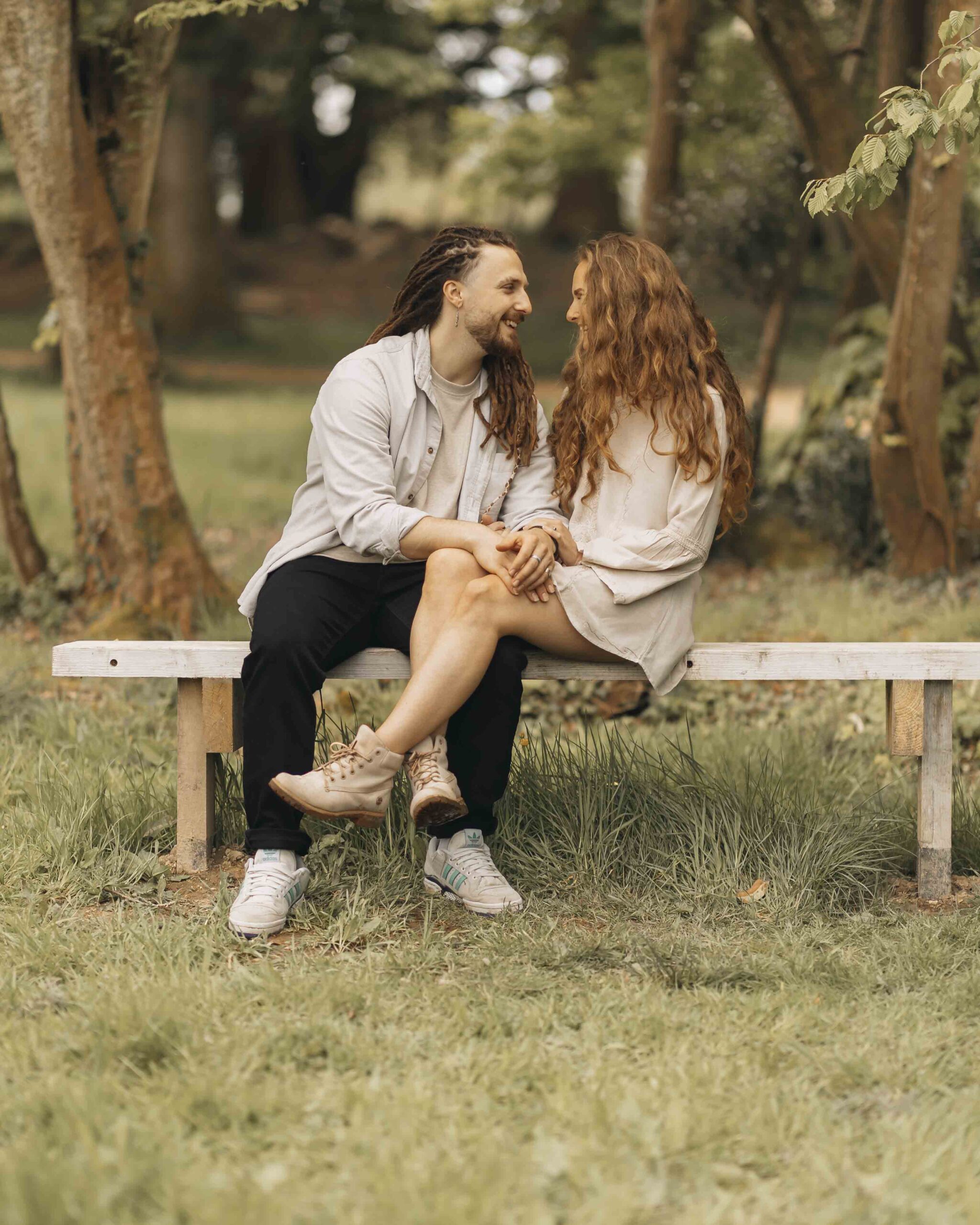 engagement shoot couple sat on bench smiling at each other