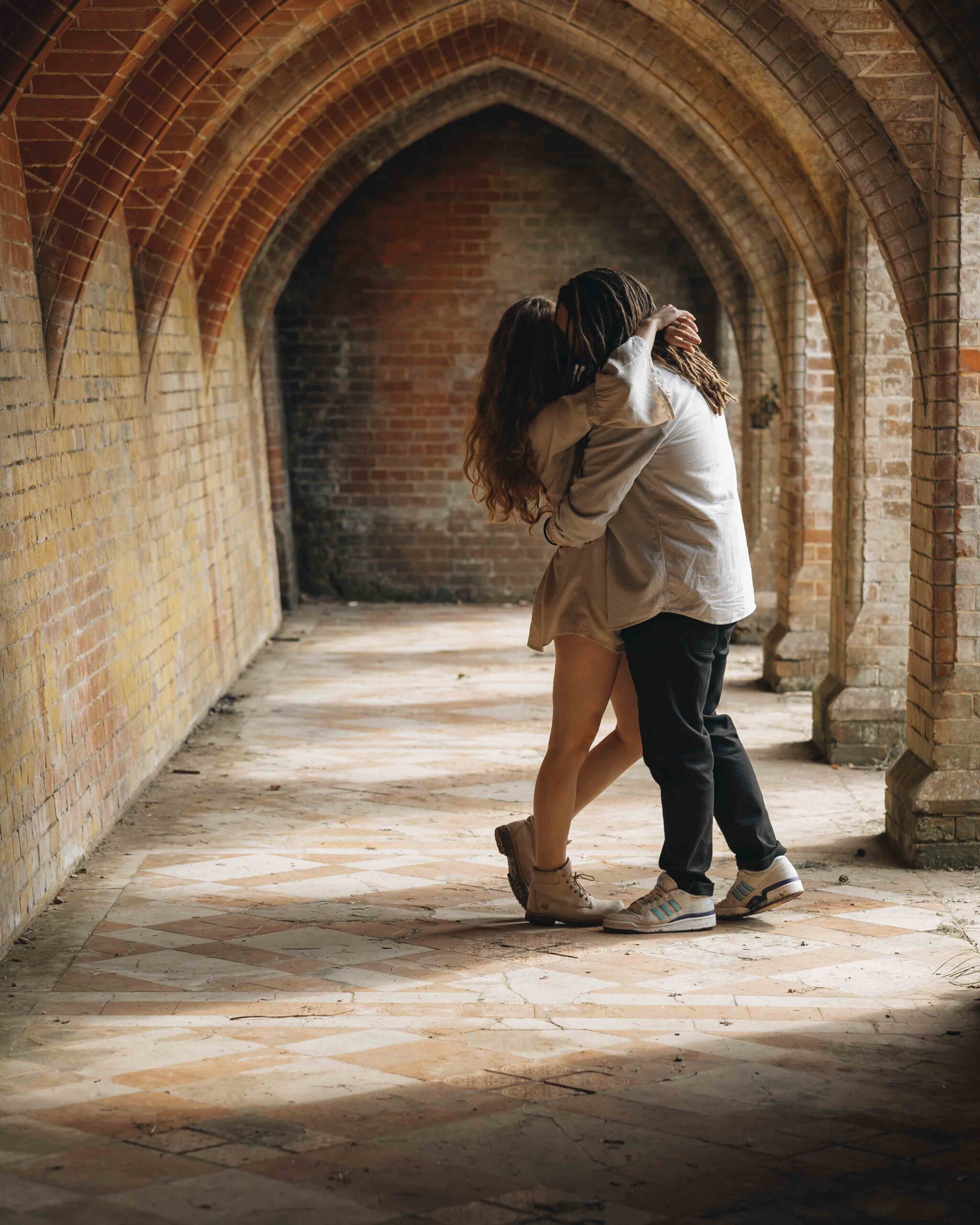 engaged couple embracing under brick arches