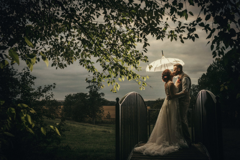 Bride and groom standing under a lit up umbrella